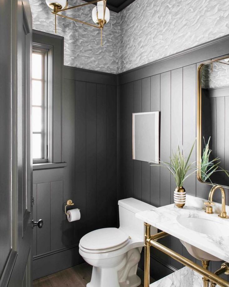 a white toilet sitting next to a sink in a bathroom under a golden framed mirror