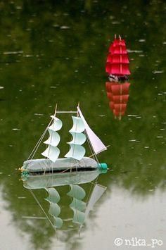 a small boat floating on top of a lake next to a red and white sailboat