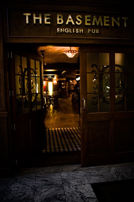 the basement english pub is lit up at night with its lights on and dark floors