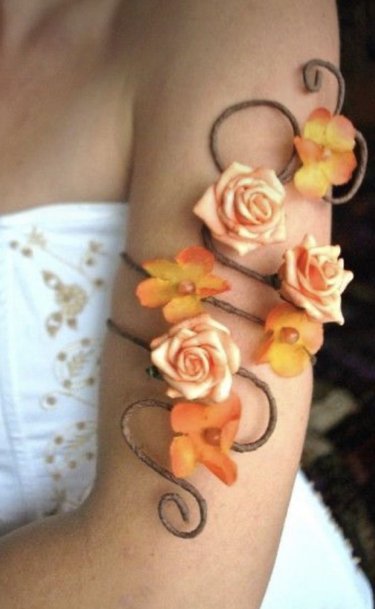 a woman with flowers on her arm is wearing a white top and orange bracelets