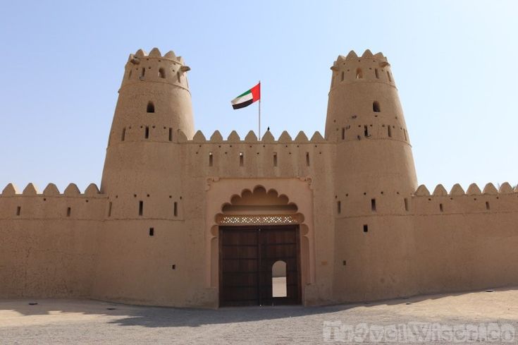 the entrance to an old castle with a flag on it's roof and two towers