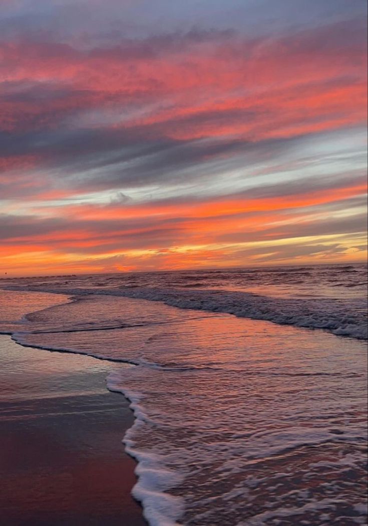 the sun is setting at the beach with waves coming in