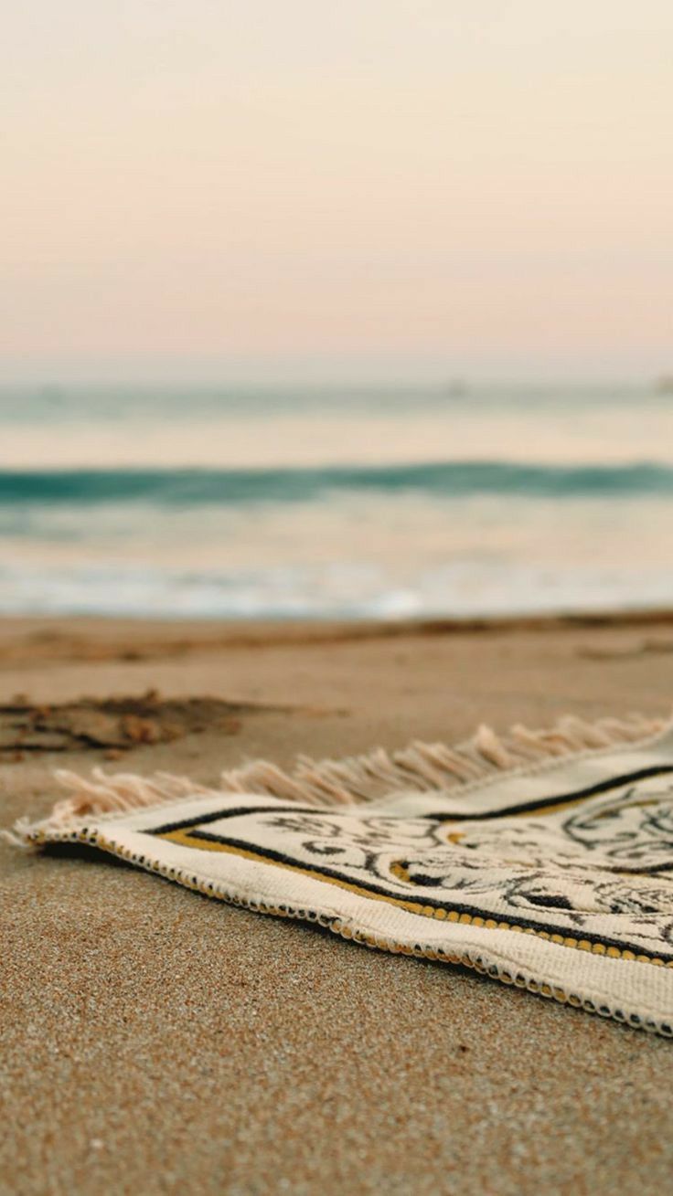 a blanket laying on the beach next to the ocean