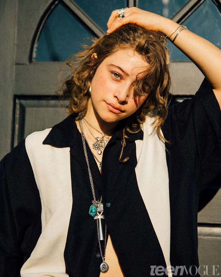 a young woman is posing in front of a door with her hands on her head