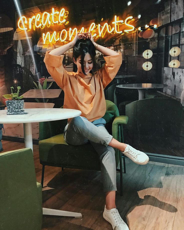 a woman sitting at a table in front of a neon sign that reads create moments