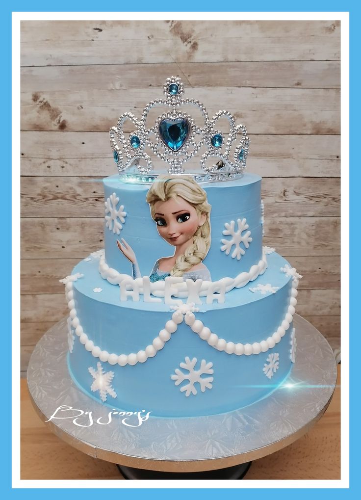 a frozen princess cake with blue frosting and white icing on the bottom tier