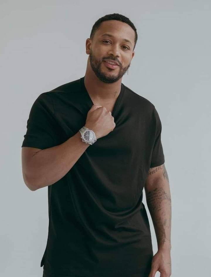 a man with a watch on his left hand is posing for the camera while wearing a black t - shirt