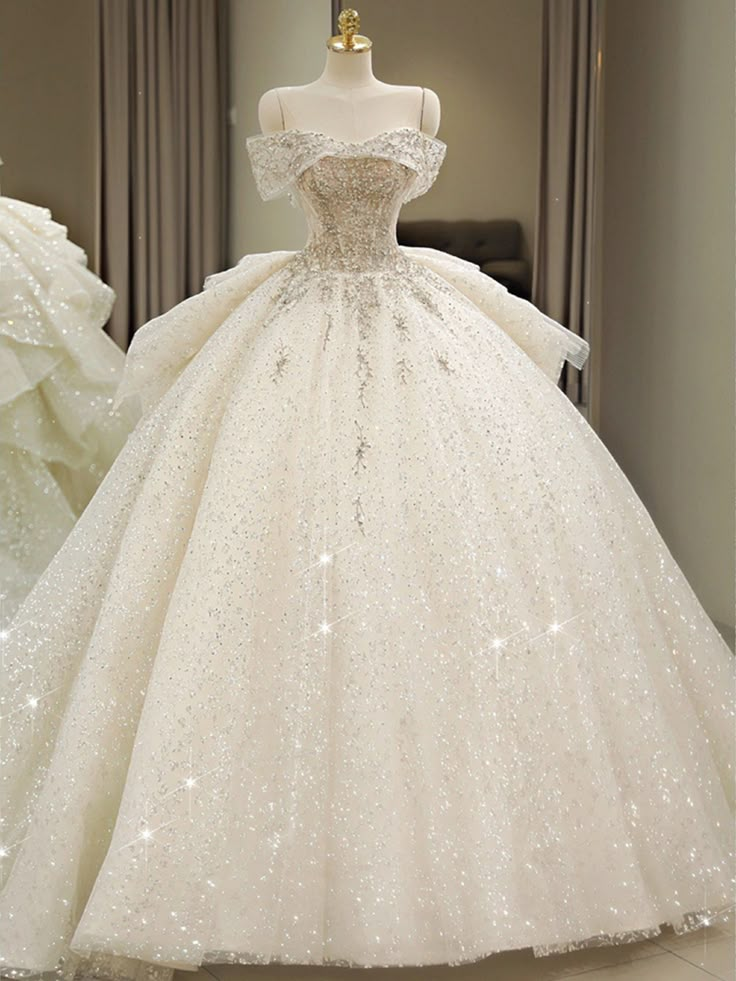 a white ball gown with sequins on the skirt and off - the - shoulder