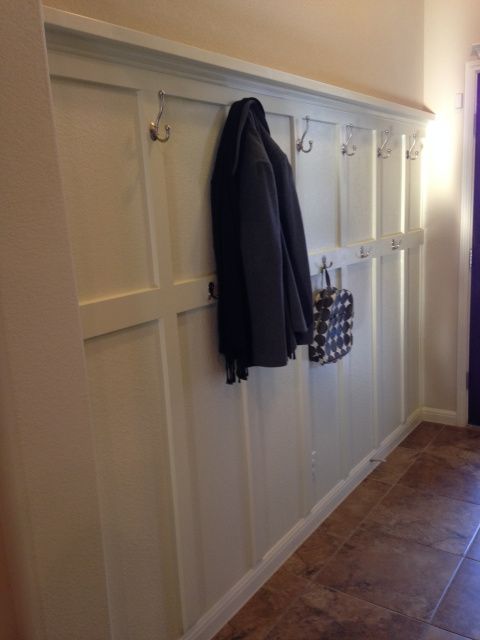 a coat rack with two coats hanging from it's hooks on the wall next to a purple door