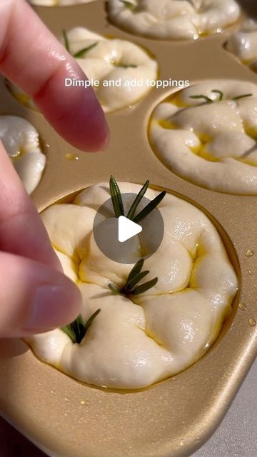 a person placing some food in a muffin tin with rosemary sprigs on top