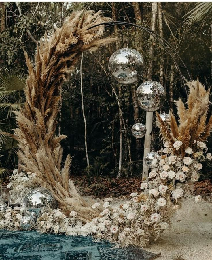 an outdoor wedding arch decorated with flowers and disco balls