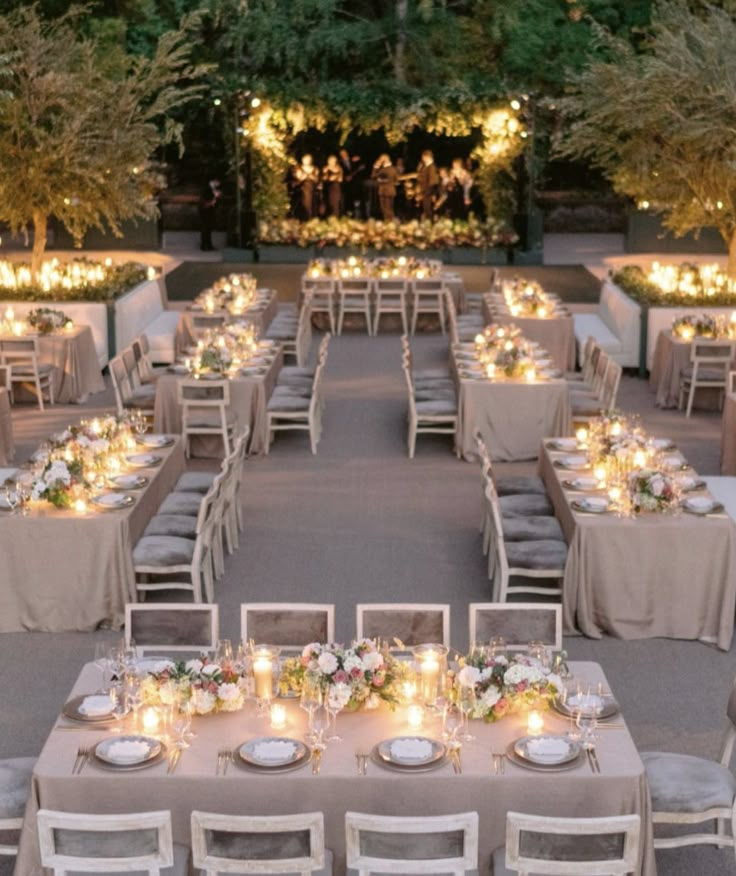 an outdoor dining area with tables, chairs and candles lit up at the end of each table