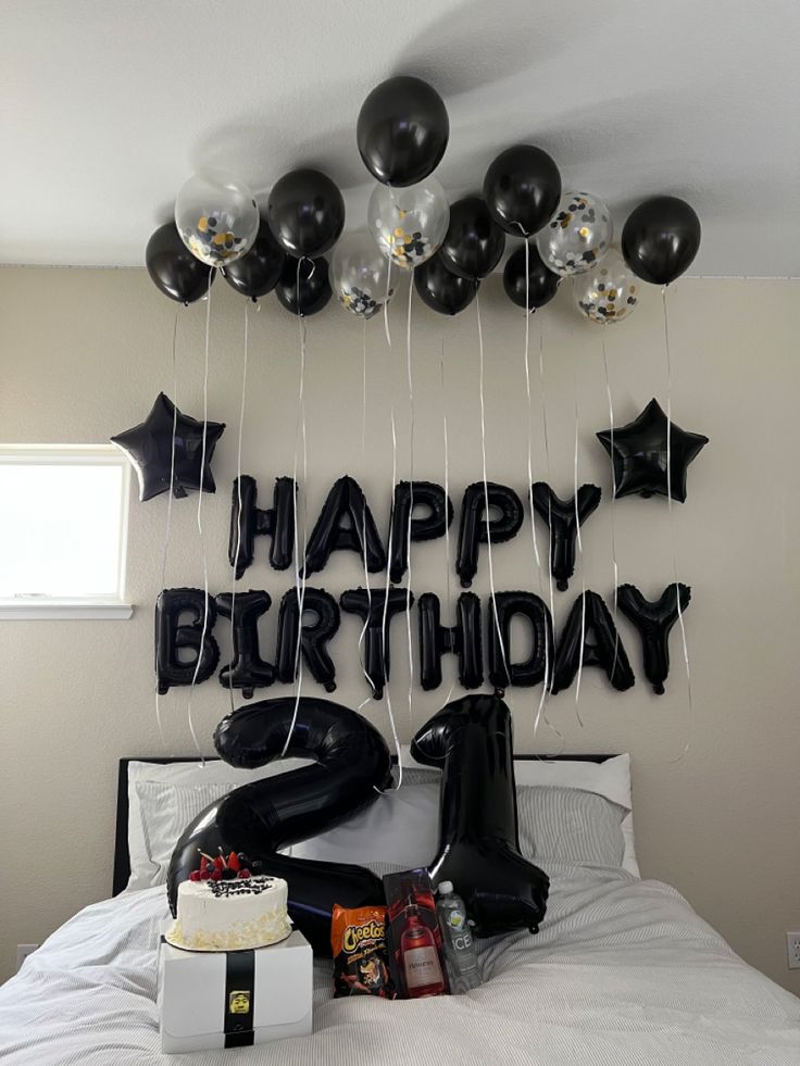 black and white balloons are hanging from the ceiling above a bed with presents on it