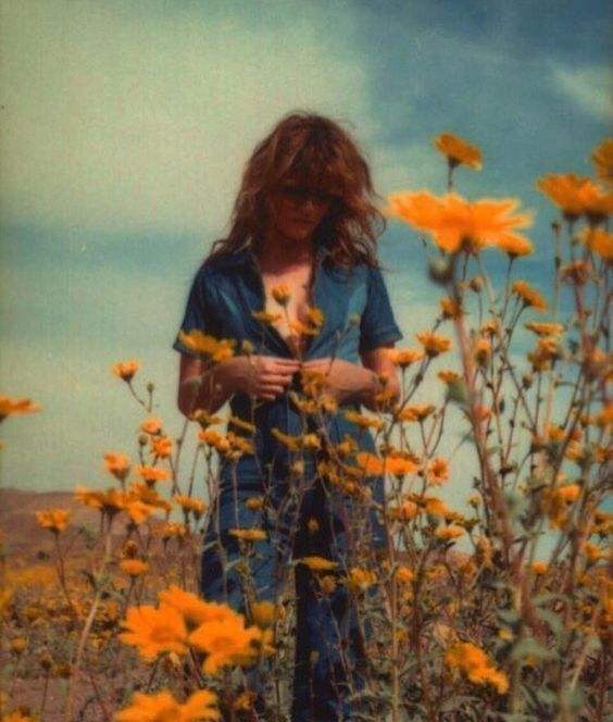 a woman standing in a field of yellow flowers