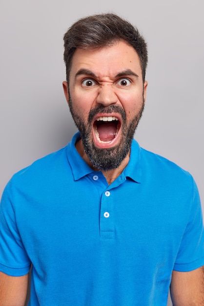 a man making an angry face with his mouth wide open while wearing a blue polo shirt