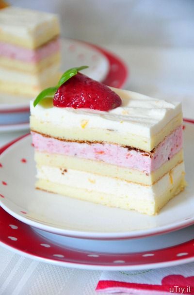 two pieces of cake on a red and white plate with strawberries in the middle