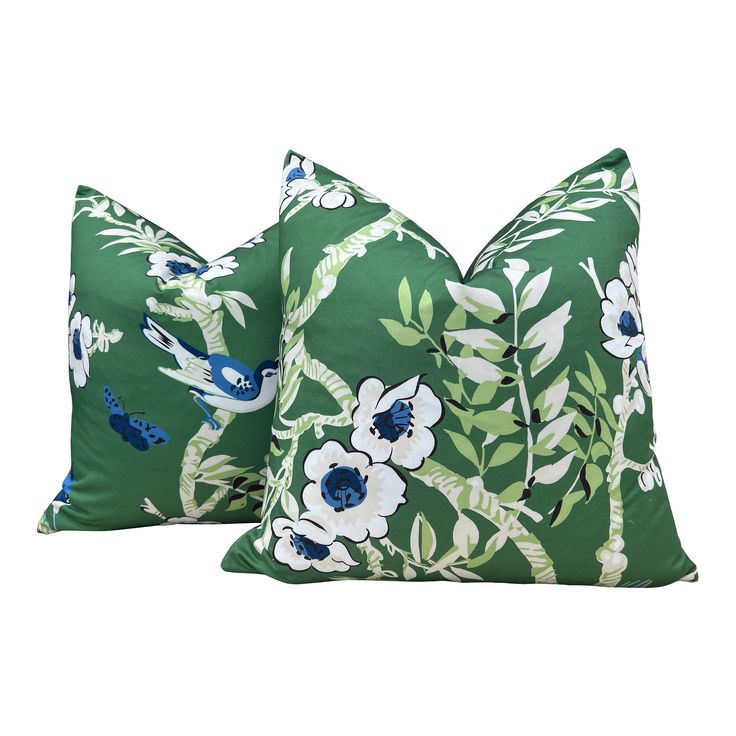 two green pillows with blue and white flowers on them, one is in the shape of a bird