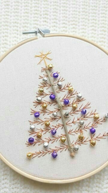 a cross stitch christmas tree on a white background with gold and purple beads in the shape of a star