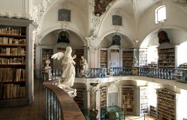 an old library with statues and bookshelves