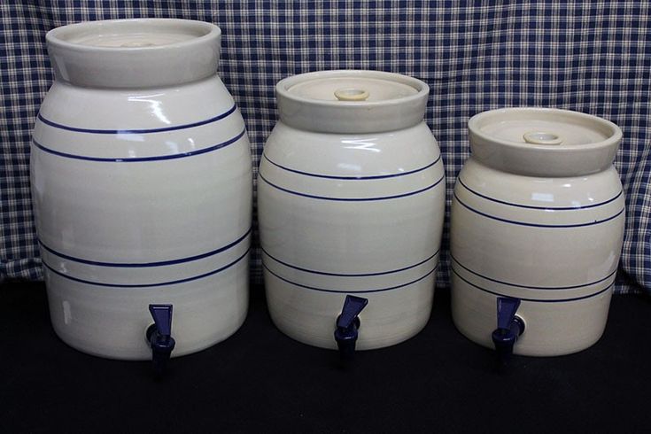 three white vases are lined up against a blue checkered wall