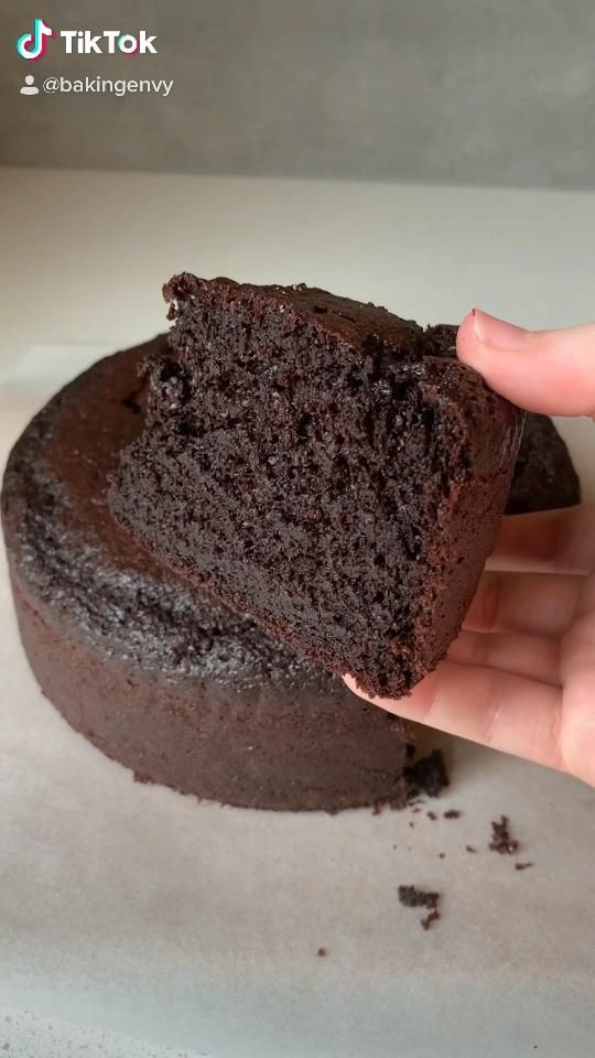 a hand holding a piece of chocolate cake