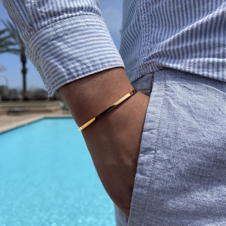 a man wearing a gold bracelet near a pool