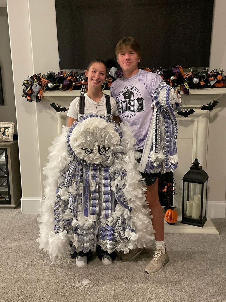 two young people standing next to each other in front of a fireplace decorated for halloween