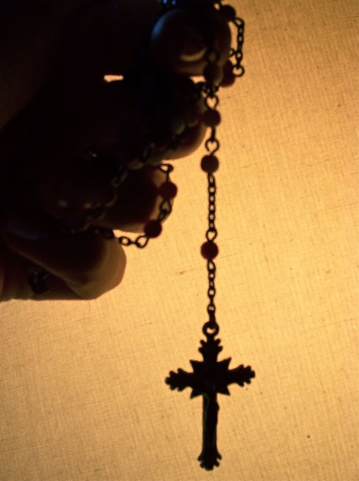 a person is holding a rosary with a cross hanging from it's end and the light shining on them