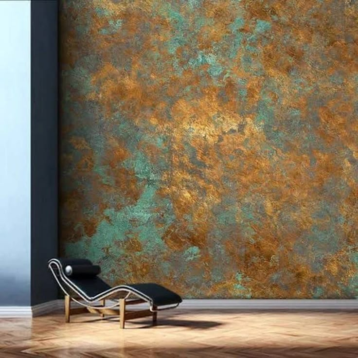 a chair sitting in front of a wall with gold paint on it