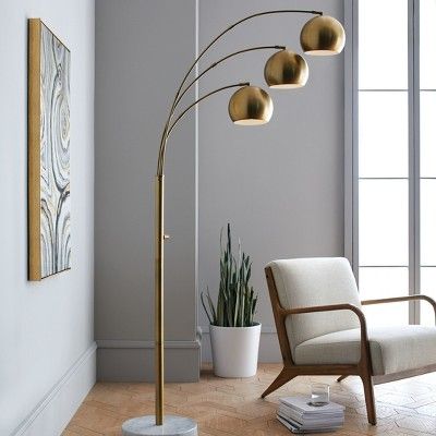 a living room with a chair, lamp and potted plant on the floor in front of it