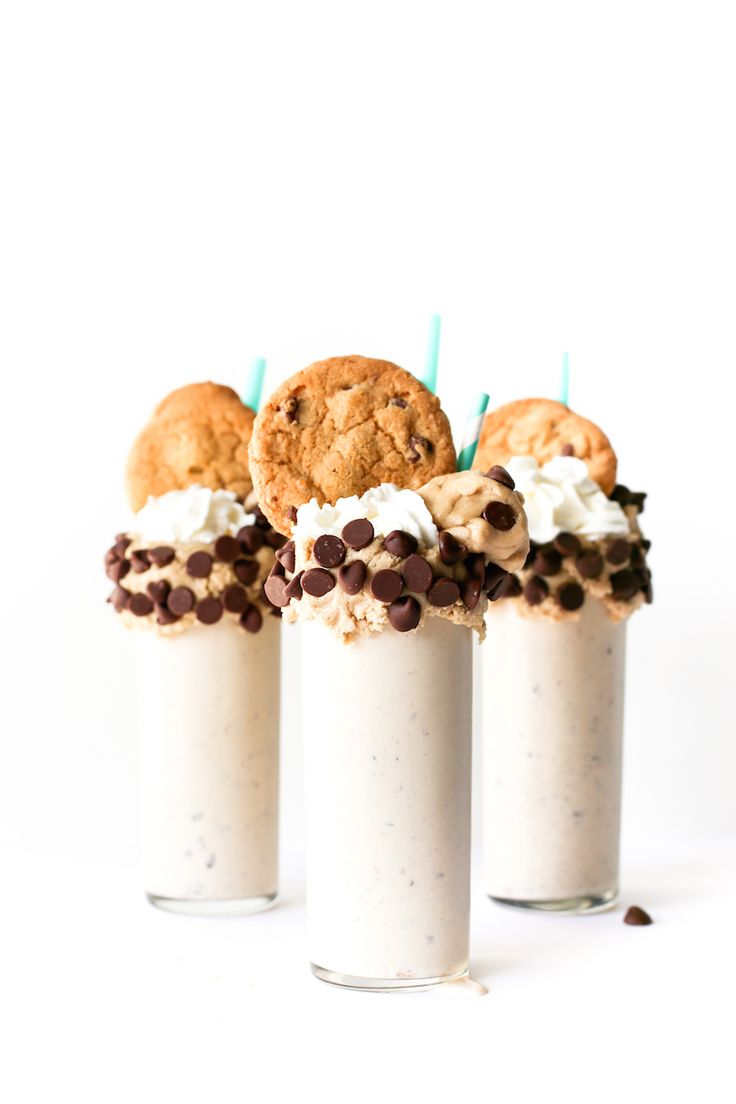 three milkshakes with cookies and ice cream in them on a white table top