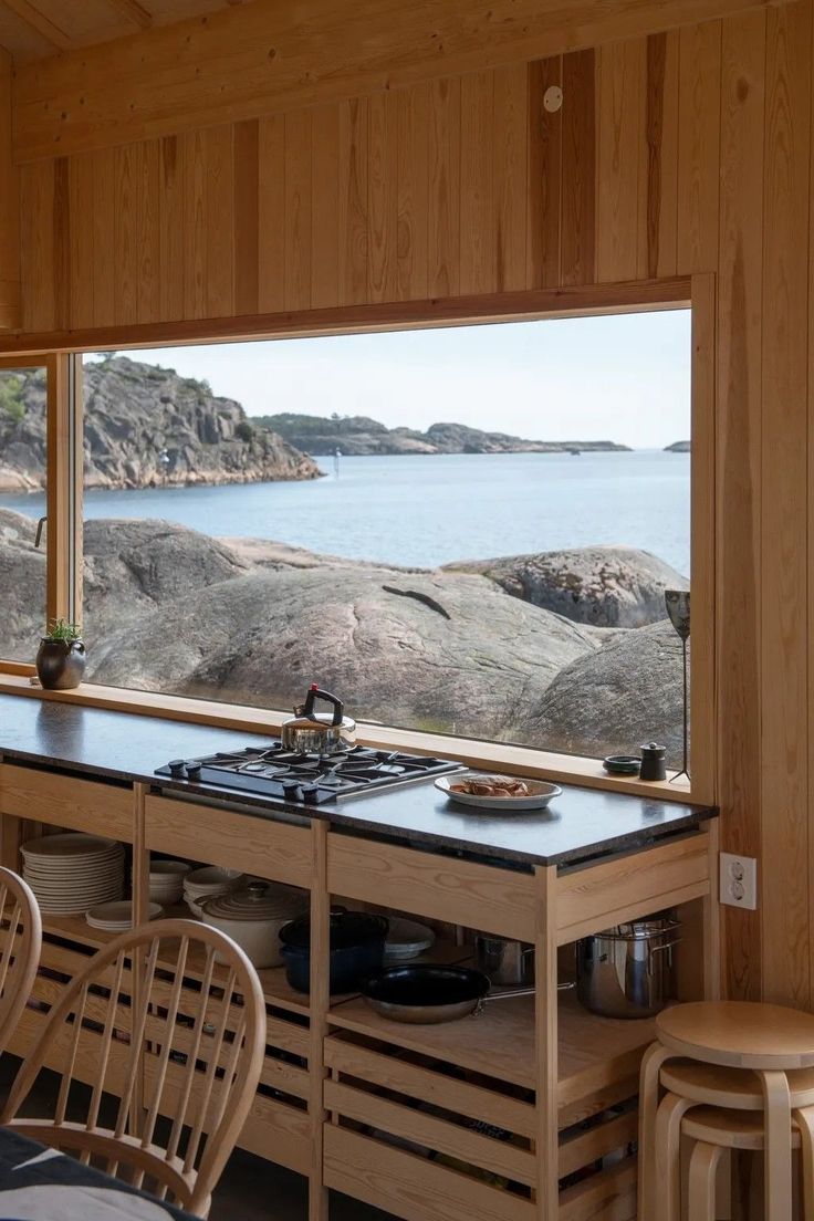 a kitchen with a stove top oven sitting next to a large window overlooking the ocean