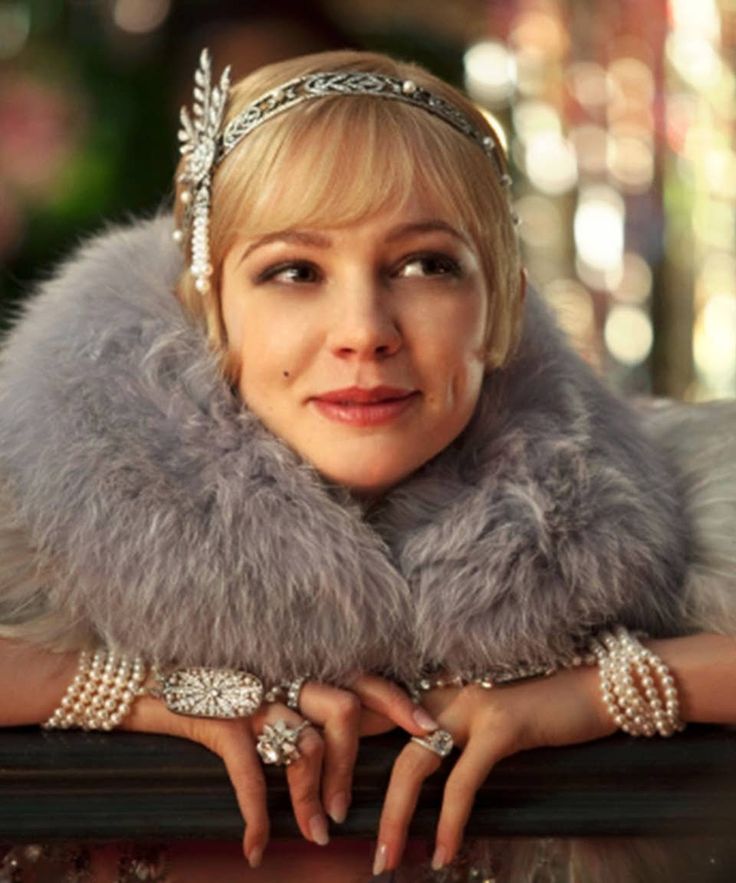 a woman wearing a fur collar and pearls on her head, posing for the camera