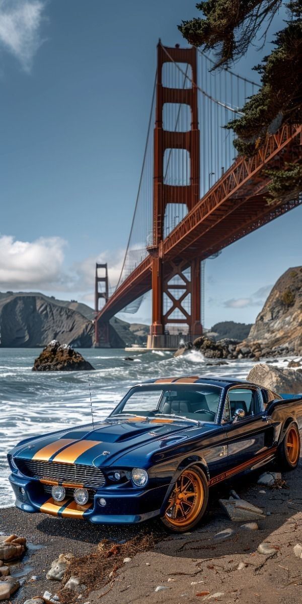 an old mustang car parked on the beach next to the golden gate bridge