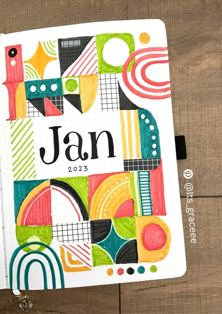 an open notebook with the word jan on it and colorful designs in front of wood planks