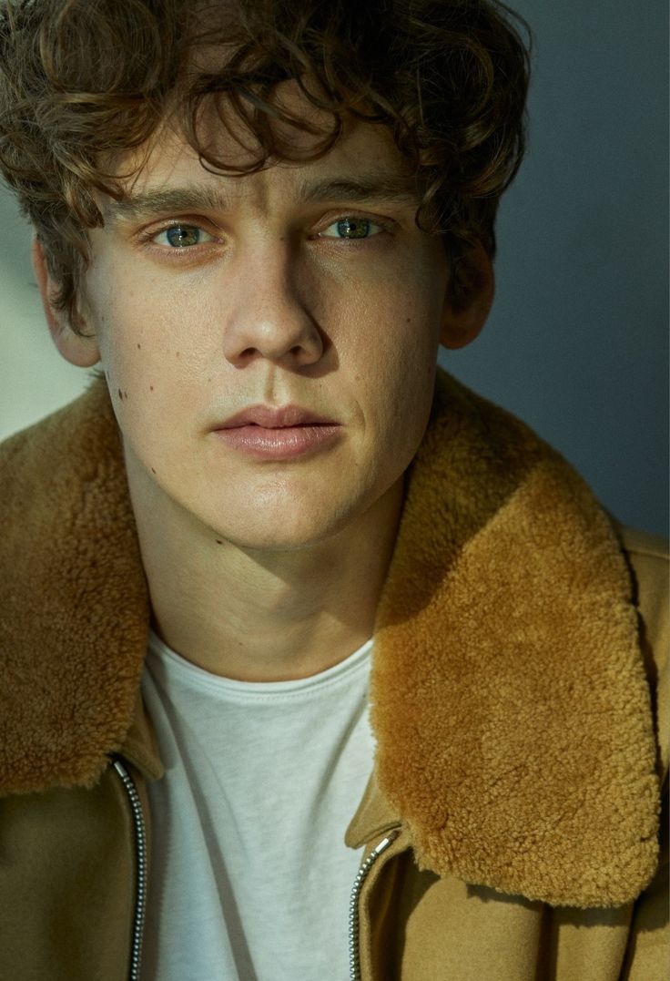 a young man with curly hair wearing a jacket