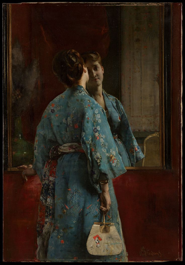 a woman in a blue kimono holding a white purse looking at herself in the mirror