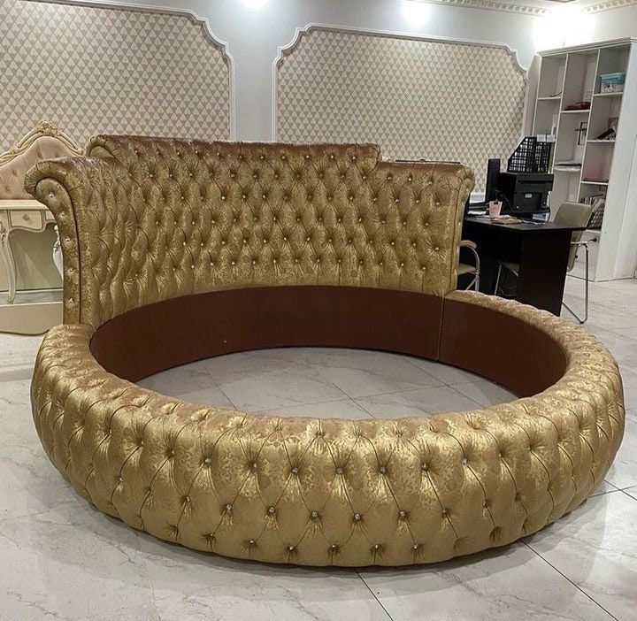 a gold couch sitting on top of a white floor next to a book shelf and desk