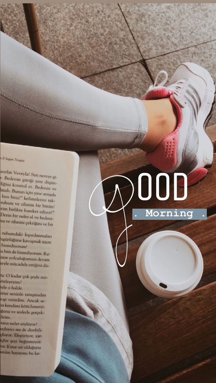 a person sitting on a bench reading a book and holding a coffee cup with the words good morning