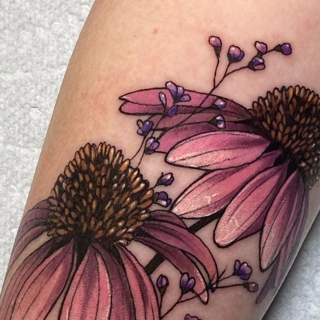 a close up of a person's leg with tattoos on it and two pink flowers