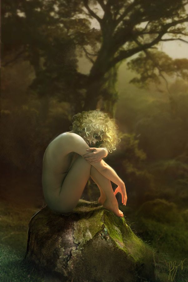 a naked woman sitting on top of a moss covered rock in front of a tree