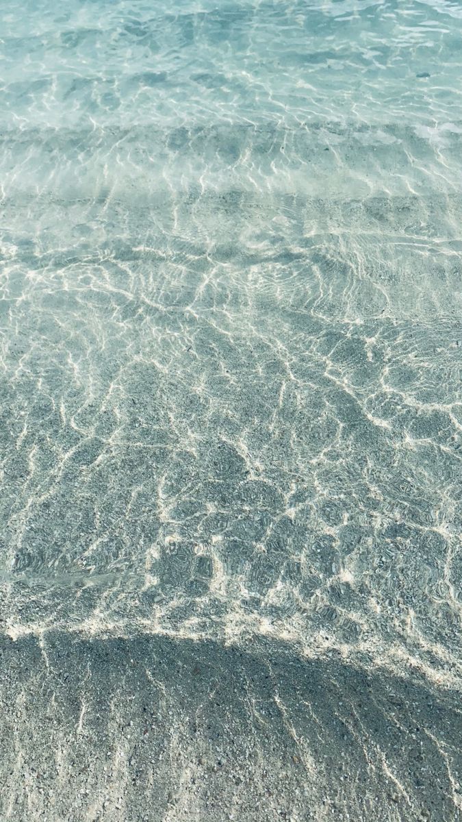 the water is very clear and blue in this beach scene, with waves crashing on the sand