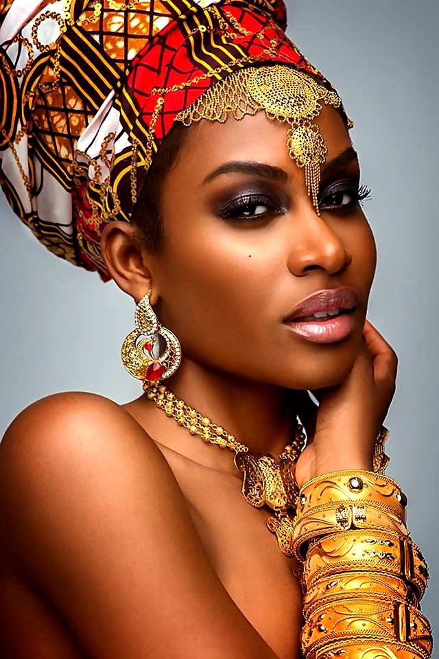 an african woman wearing gold jewelry and a red headdress is posing for the camera