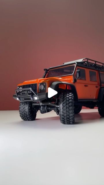 an orange toy truck on a white surface with a red wall in the back ground