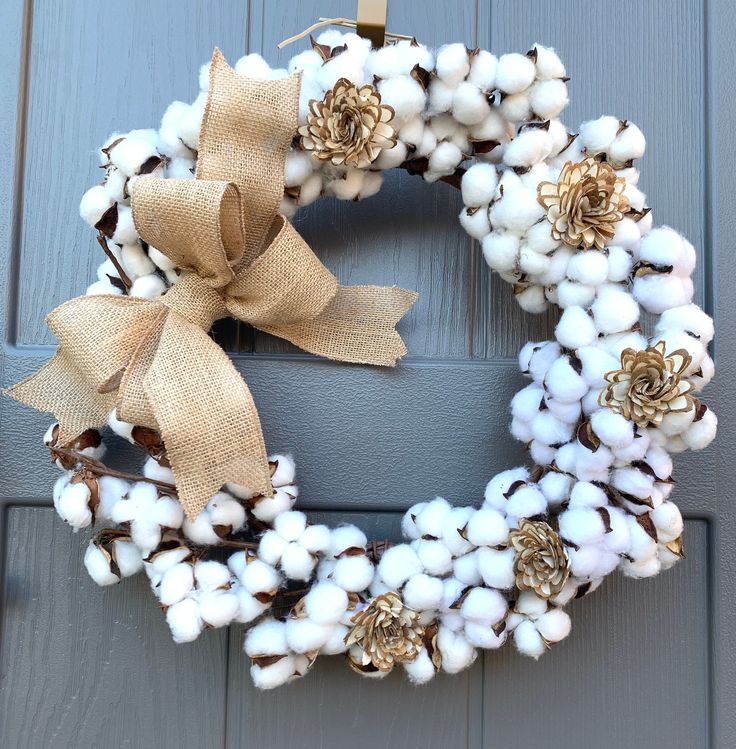 a cotton wreath is hanging on the front door with burlocks and gold accents