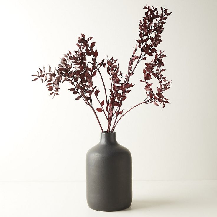 a gray vase with red flowers in it on a white tableclothed surface,