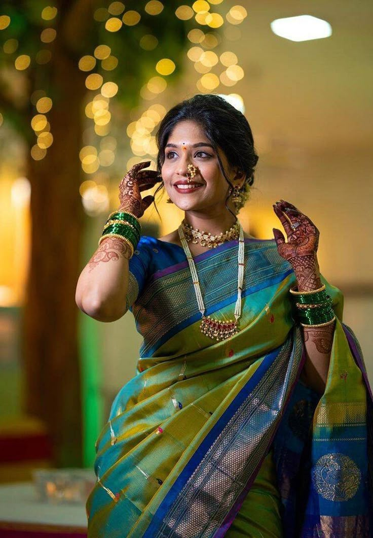 a woman in a green sari holding her hands up to her ear and smiling