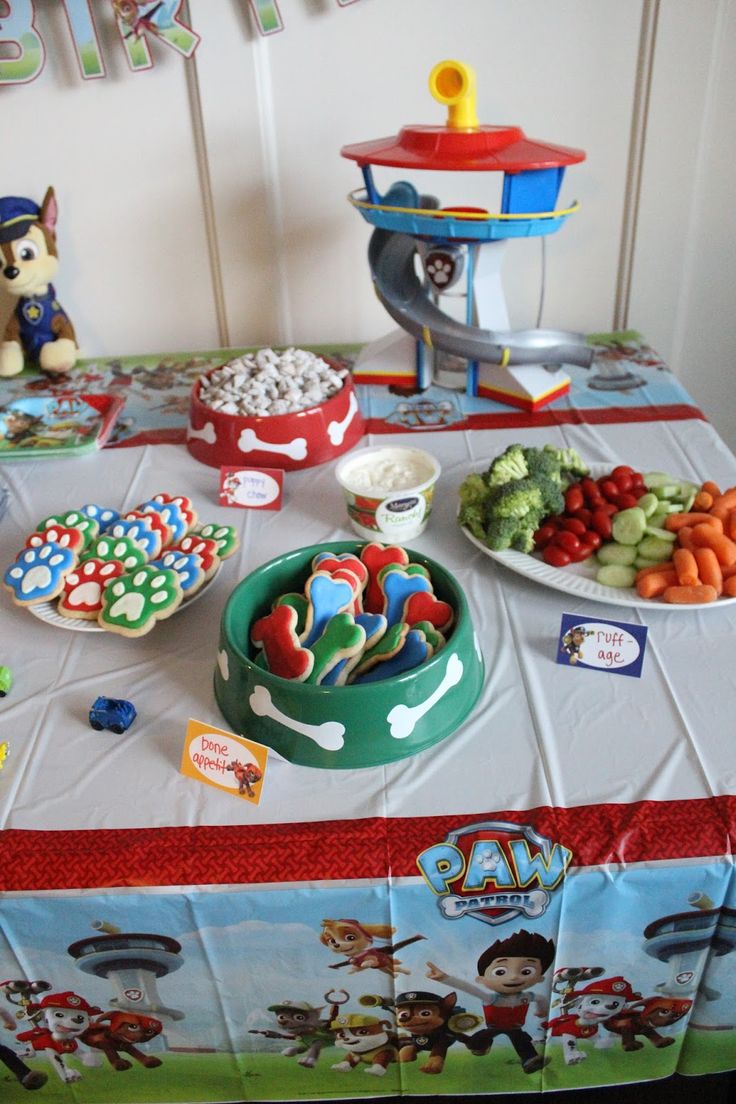 a table topped with lots of toys and food on top of a white table cloth