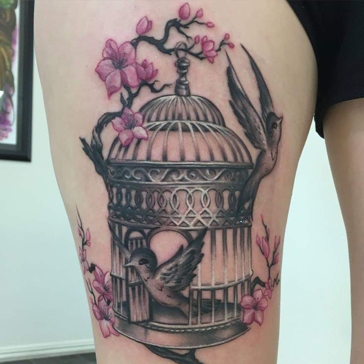 a woman's thigh with a bird in a cage and flowers on the side