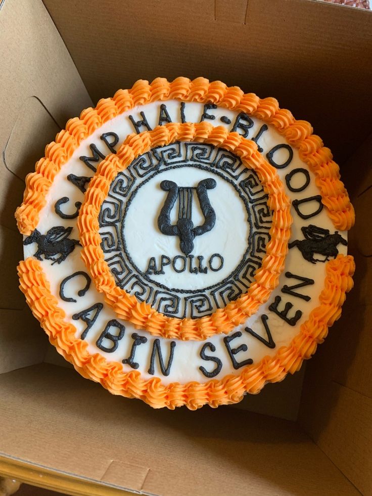 an orange and white cake sitting in a box on top of a cardboard box with the words camp waterfood cabin seven